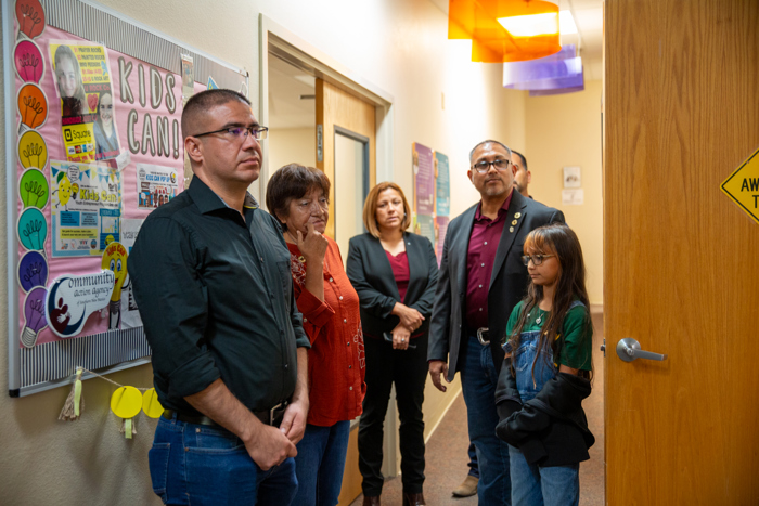 The group pauses at the wall displays in the hallway.