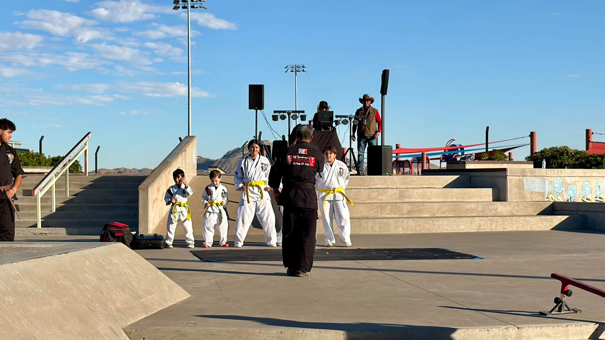 Young karate students in white uniforms and yellow belts perform a demonstration with their instructor