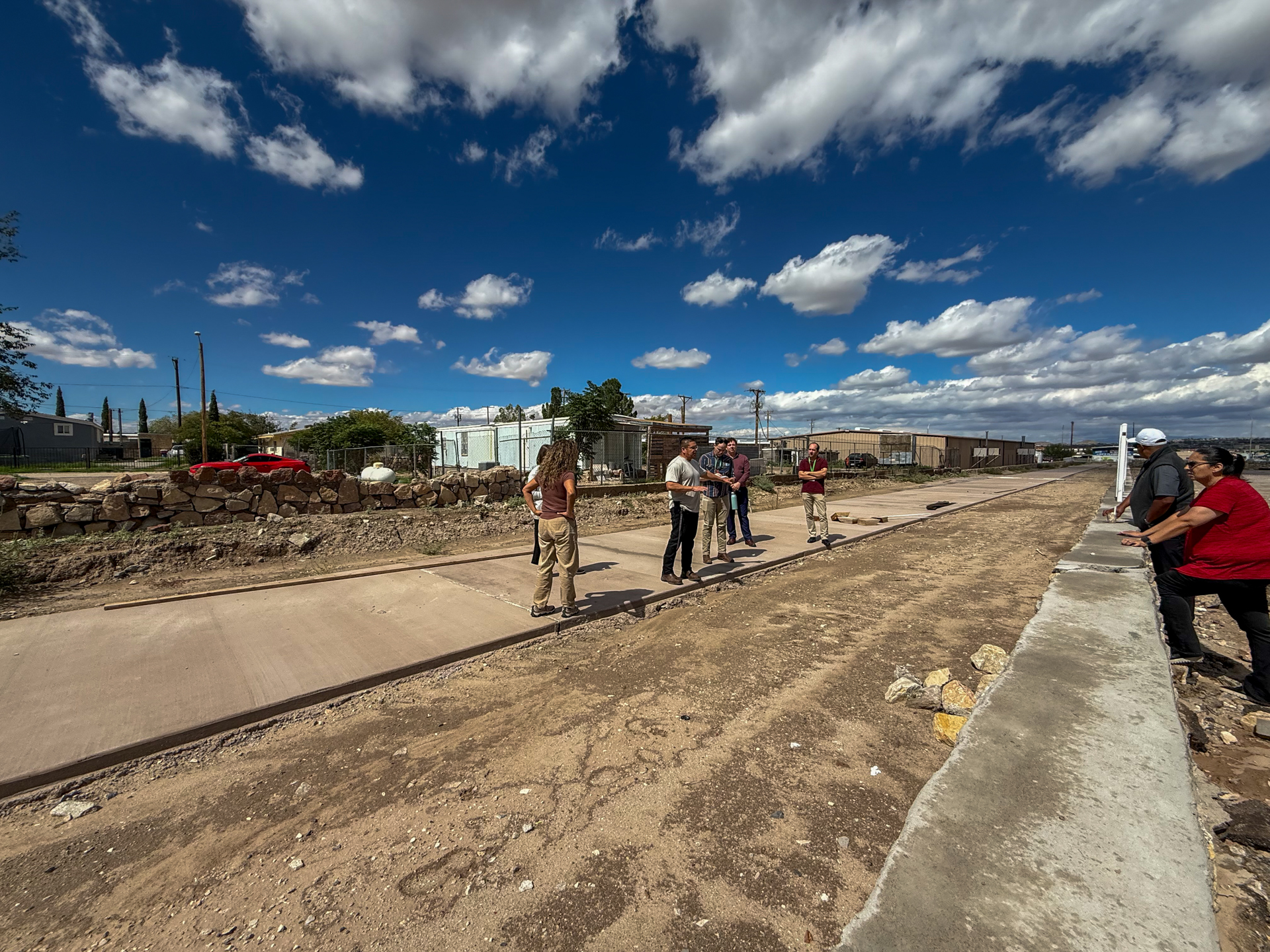 Representatives walking along a newly paved path under a blue sky