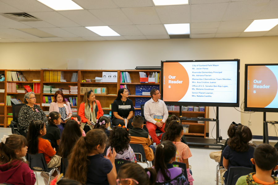 The five community readers take their seats beside the “Our Readers” slide.