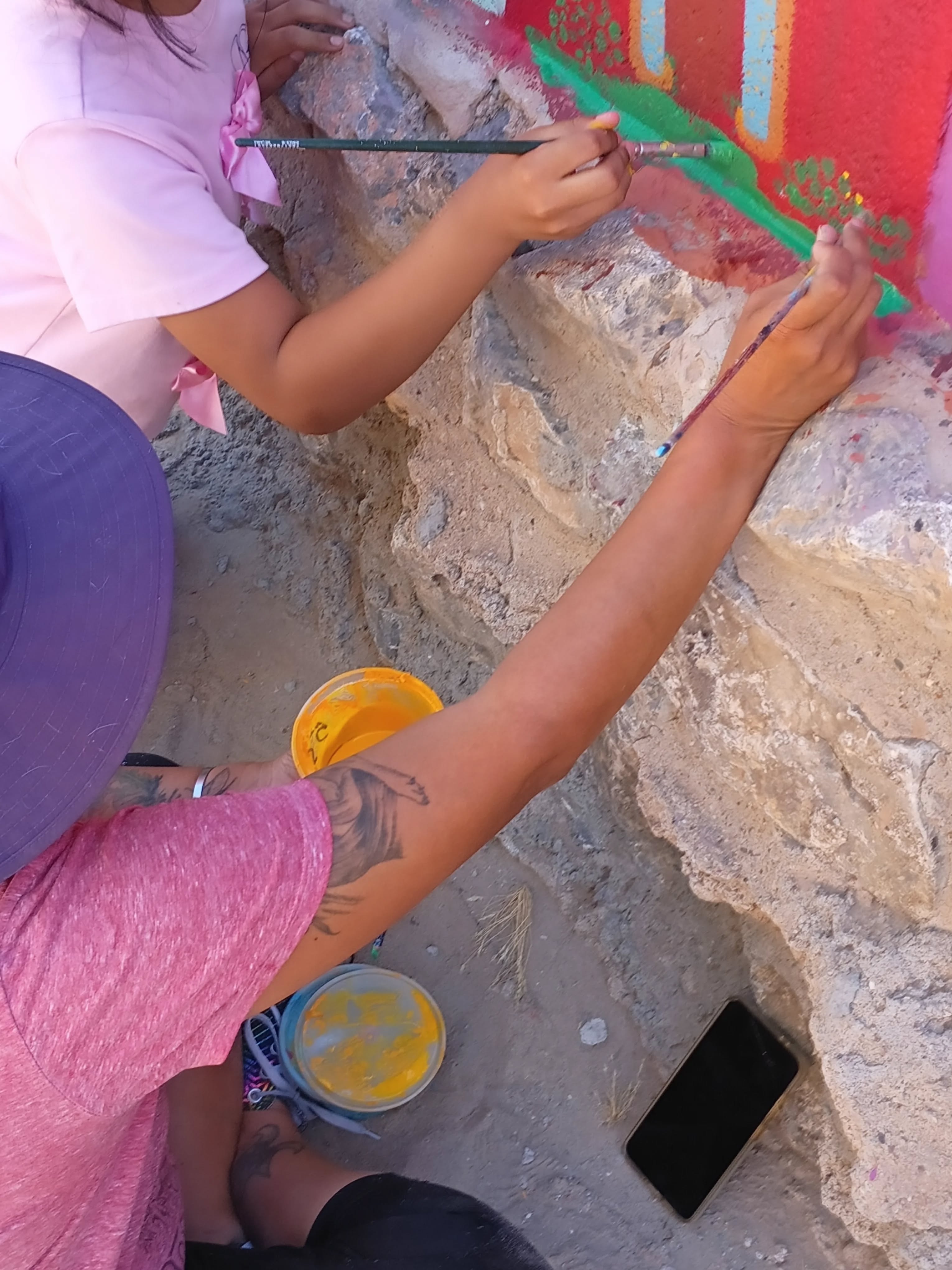 Volunteers painting along the base of the wall.