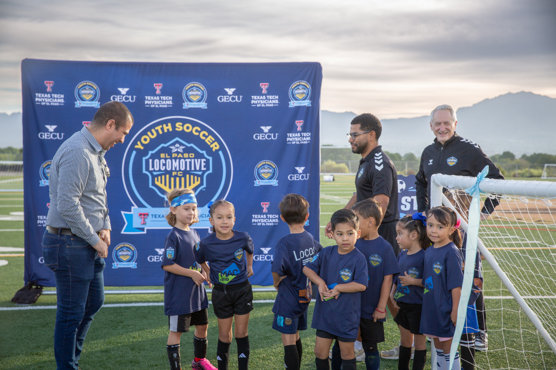 Mayor Javier Perea talks with youth soccer players in front of the El Paso Locomotive FC Youth Soccer backdrop / El alcalde Javier Perea platica con los jugadores de First Stop frente al fondo de El Paso Locomotive FC Youth Soccer
