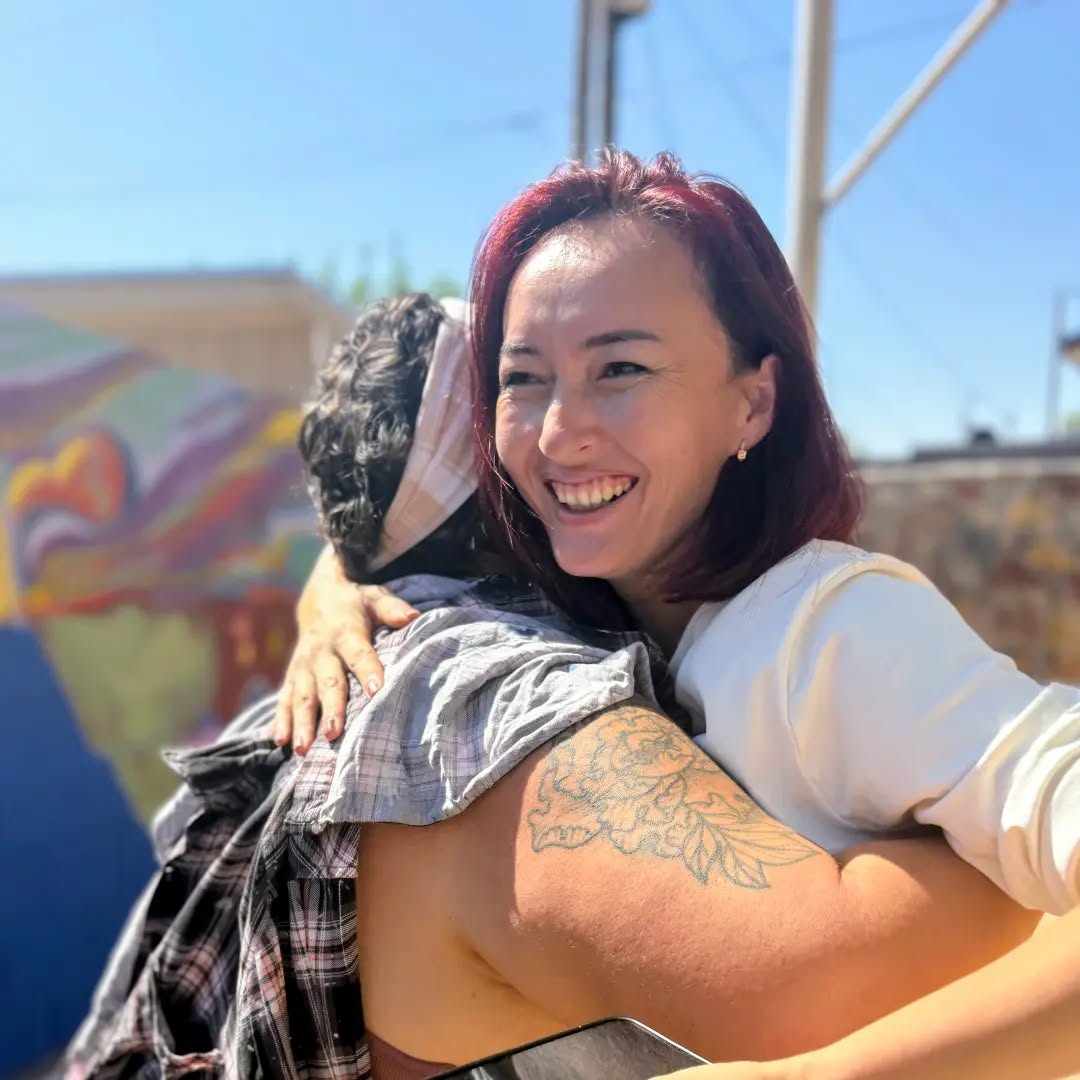 Two people share a hug at the mural reveal celebration.