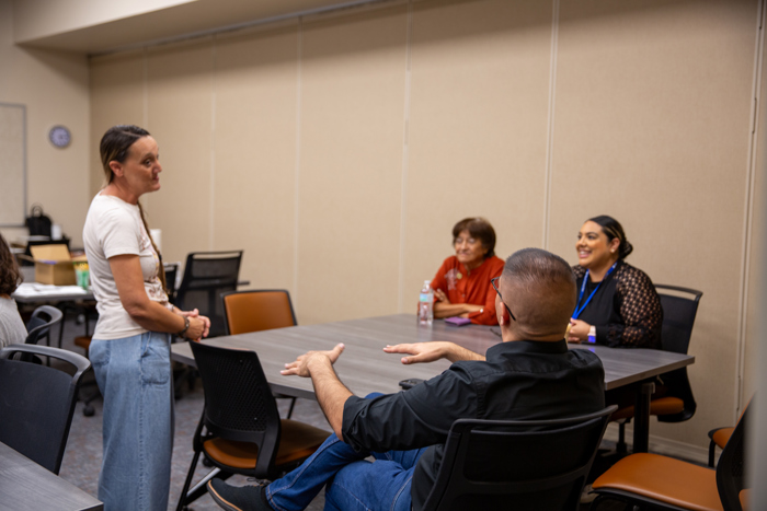 A speaker shares information while guests listen at the table.