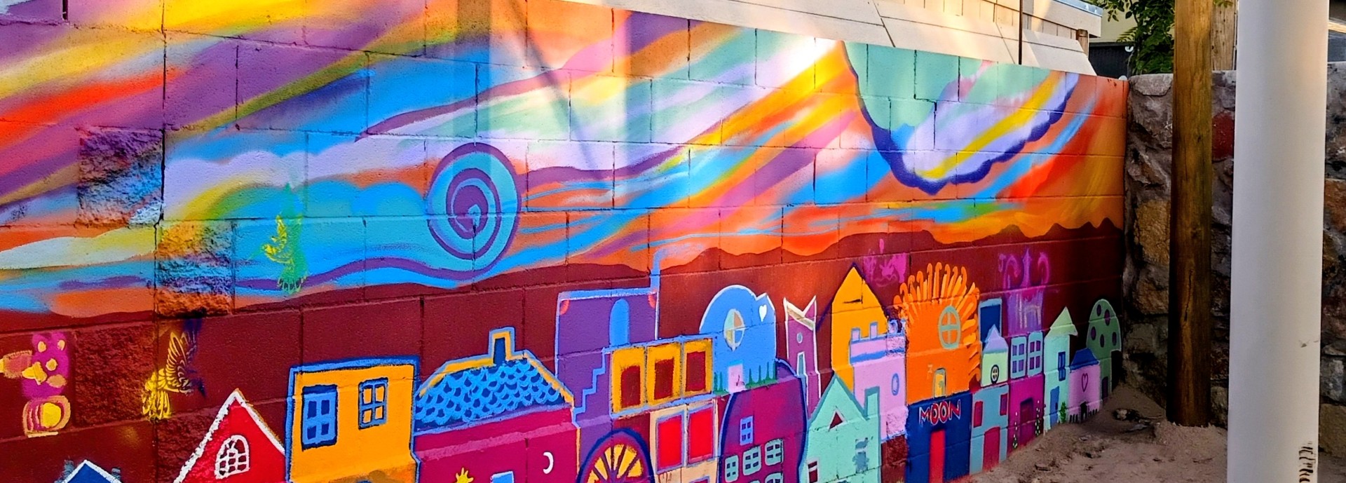 Wide view of the finished mural, with a swirling sky above rows of colorful casitas.