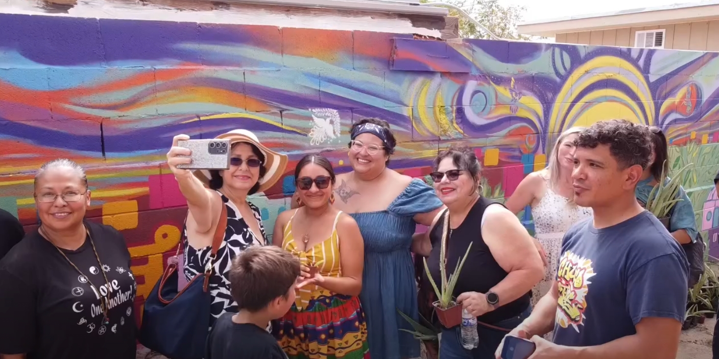 Volunteers and neighbors pose for a group selfie in front of the mural.