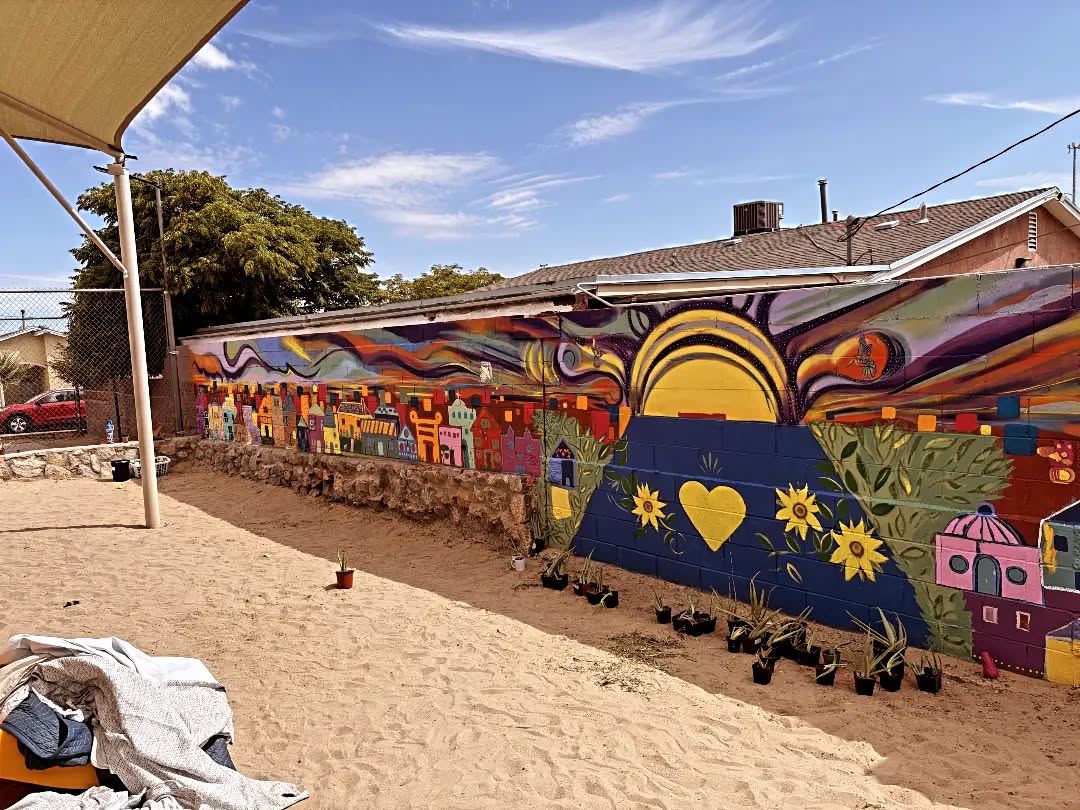 The finished mural at Las Casitas Park, with a rising sun, sunflowers and a yellow heart.