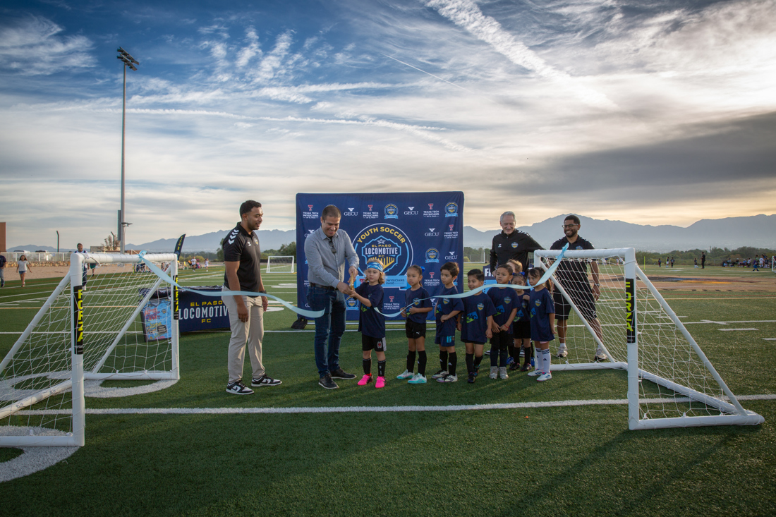 Mayor Javier Perea and young players cut a light blue ribbon stretched between two small soccer goals / El alcalde Javier Perea y los pequeños jugadores cortan un listón azul claro entre dos porterías