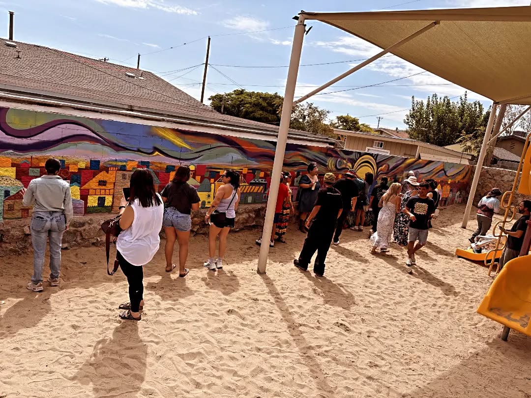 Neighbors gather in the park to look at the finished mural on reveal day.
