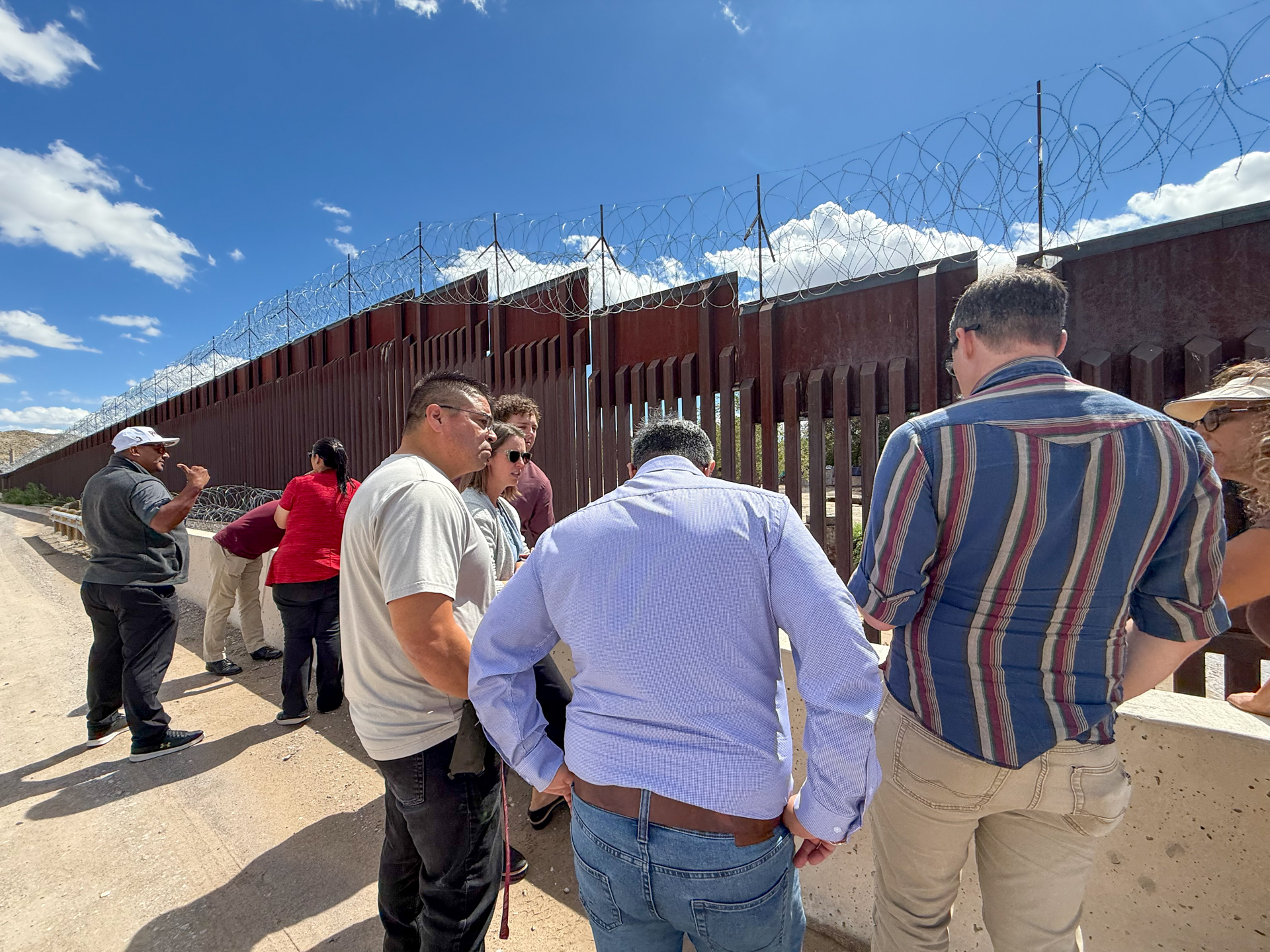 Tour participants gathered at a concrete barrier reviewing drainage
