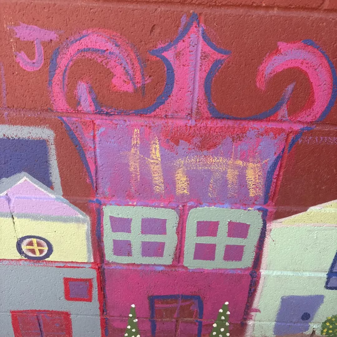 Detail of a pink casita with ornate trim and white windows.