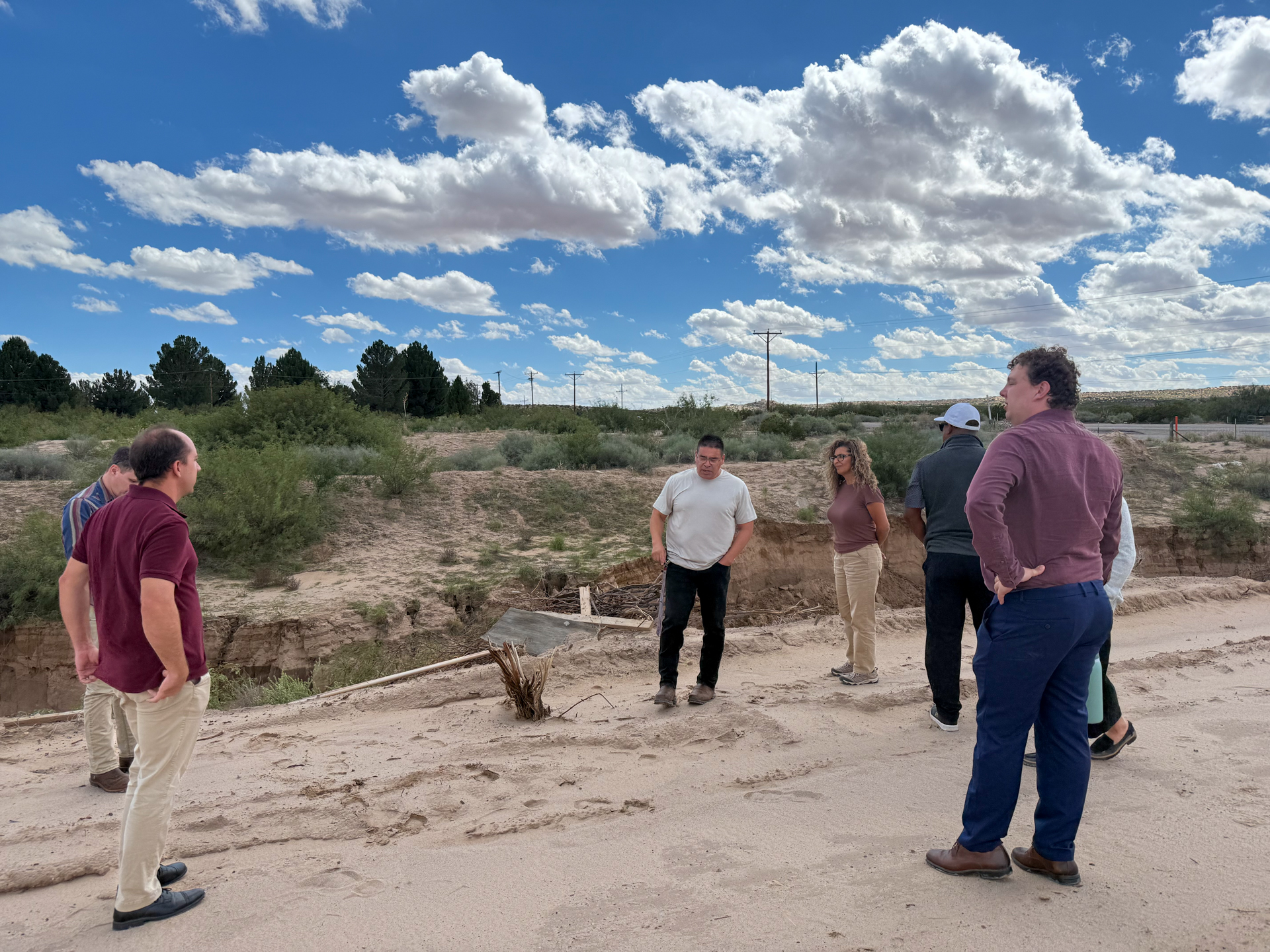 Tour participants standing beside a drainage channel during the flood project visit
