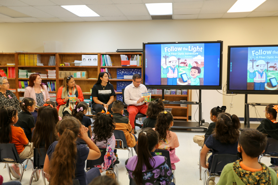 Mayor Javier Perea holds up the book as its cover appears on the classroom monitors.