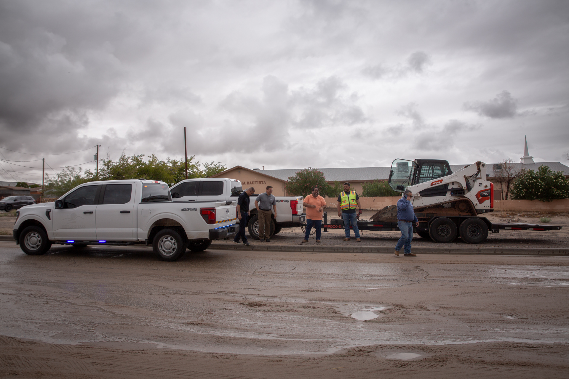 Crew and equipment on a muddy street after the storms