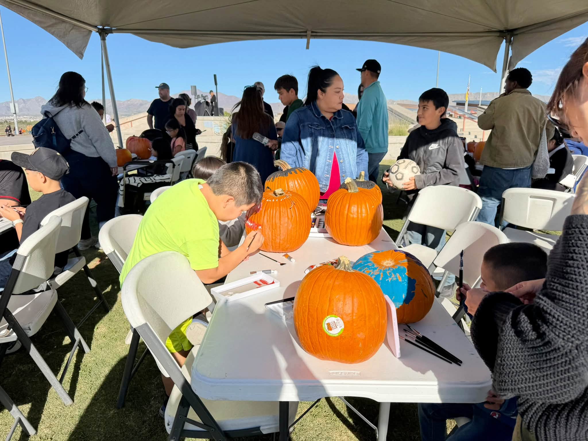 A young boy carefully paints a pumpkin at a craft table